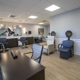 A modern salon interior featuring styling stations and comfortable seating.