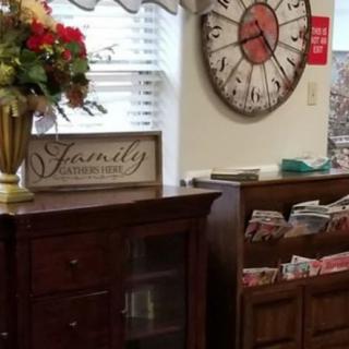 A cozy room with wooden furniture, featuring a large decorative clock and a vase of flowers.
