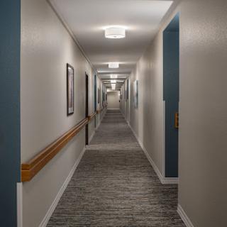 A well-lit, spacious hallway featuring carpeted floors and doors on either side.