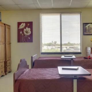 A clean and organized hospital room with two beds and a window view.
