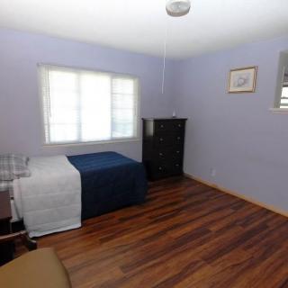 A minimalist bedroom with a single bed, dresser, and hardwood flooring.