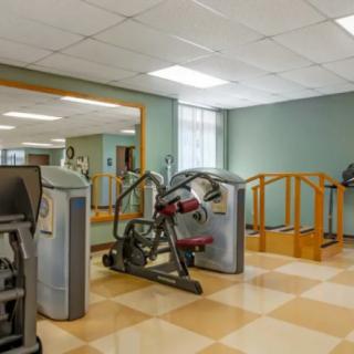 A gym room equipped with various fitness machines and a large mirror.