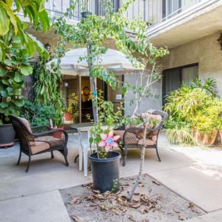A cozy outdoor patio with comfortable seating surrounded by lush greenery.