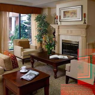 A cozy living room with elegant furniture, a fireplace, and greenery.