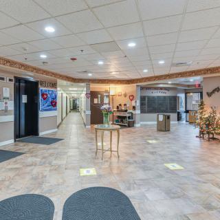 A spacious lobby with tiled flooring, a reception desk, and decorative elements along the walls.