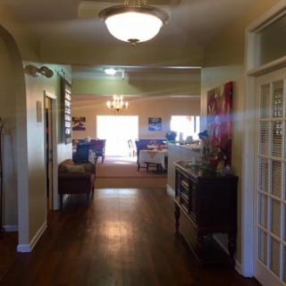 A cozy home interior featuring a well-lit hallway leading into a living room, with stylish furniture and wooden flooring.