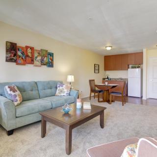 A cozy living room with a sofa and coffee table, adjacent to a small dining area and kitchenette.