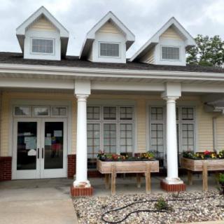 A front view of a building with columns and planters under a cloudy sky.
