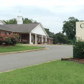 View of a building surrounded by grass and trees, with a clear sign visible.