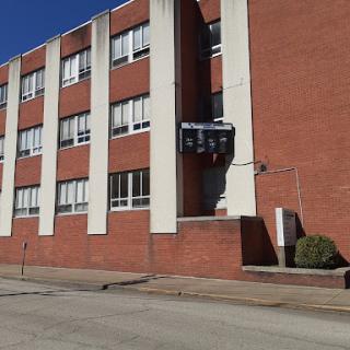 A view of a brick building, likely a school, featuring large windows and a clear blue sky.