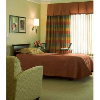 A cozy hotel room with a single bed, armchair, and decorative wall art.