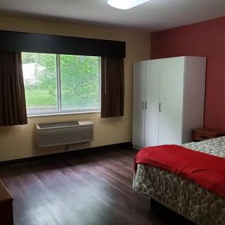 A cozy bedroom with a large window, wardrobe, and bed.