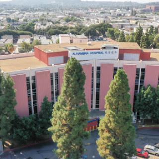 Aerial view of a modern educational institution surrounded by lush trees and a bustling cityscape.