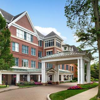 A grand entrance to a brick hotel with lush landscaping.