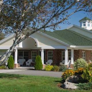 A view of a well-maintained building surrounded by greenery and colorful flowers.