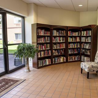 A cozy library corner with bookshelves and an armchair by the window.