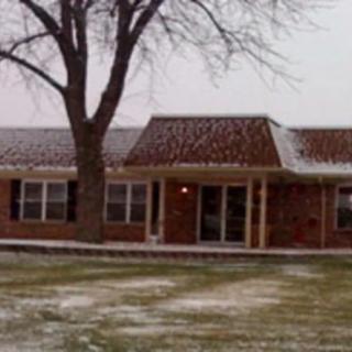A brick house with a snow-dusted lawn in winter.