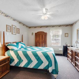 A cozy bedroom with a teal and white chevron-patterned bedspread, wooden furniture, and decorative elements.
