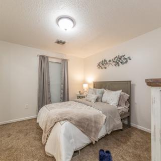 A cozy bedroom with a neatly made bed, bedside lamp, and simple decor.