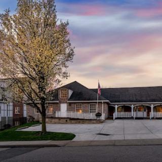 A suburban building with a tree and flag under a colorful sunset sky.