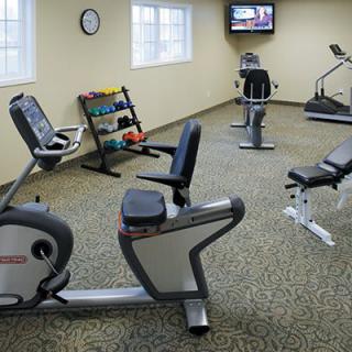 A small indoor fitness center with exercise bikes, a treadmill, and a rack of dumbbells.