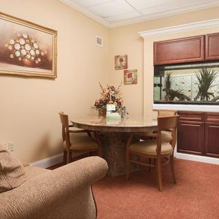 A cozy dining area featuring a round table with chairs, a sofa, and an aquarium built into the wall.