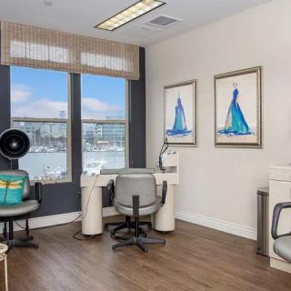A modern office space with a view of the marina, featuring stylish furniture and nautical-themed artwork.