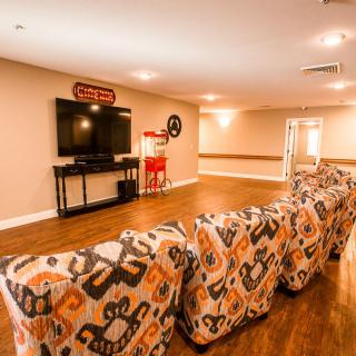 A cozy home theater setup with patterned seating and a large television.