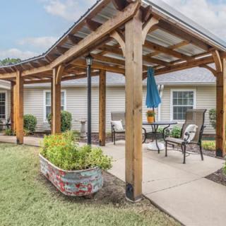 A cozy outdoor patio with a wooden pergola and seating area.