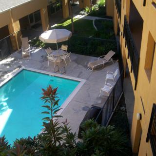 A view of an outdoor hotel pool area with sunbeds and umbrellas.