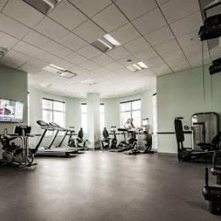 A modern gym setup featuring various exercise equipment and ample natural light.