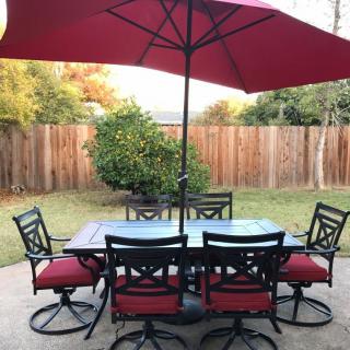 A patio set with a red umbrella and chairs in a backyard.