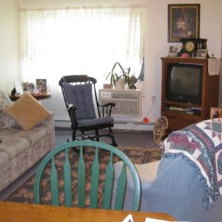 A cozy living room with various furniture pieces including a sofa, rocking chair, and television.