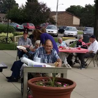 A cheerful gathering of seniors enjoying a meal outdoors.