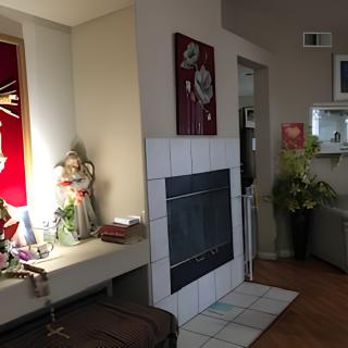 A cozy living room featuring a fireplace, decorative statues, and indoor plants.