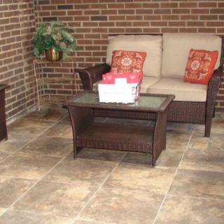 Cozy outdoor patio area with a couch, coffee table, and decorative cushions against a brick wall.