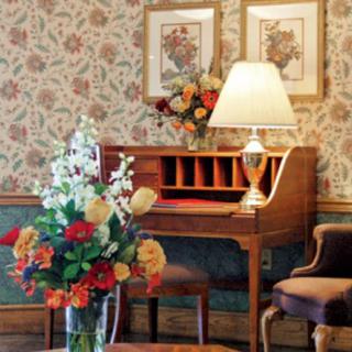 A cozy vintage-style room with a wooden desk and floral decorations.