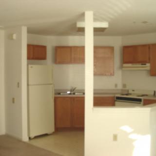 A simple apartment kitchen with wooden cabinets and basic appliances.