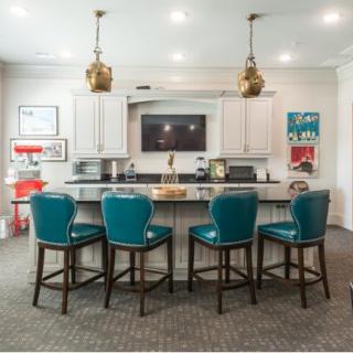 A modern kitchen with an island and teal bar stools, featuring stylish lighting and contemporary decor.