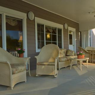 A cozy porch with wicker furniture set, including chairs and a sofa, perfect for relaxing outdoors.