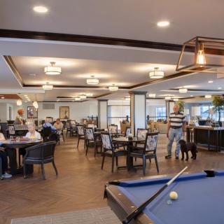 A spacious restaurant interior with a billiards table and people dining at various tables.