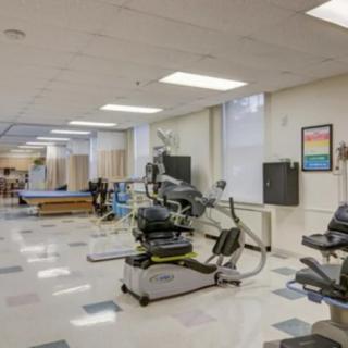 A spacious rehabilitation center equipped with various exercise machines and therapeutic tools.