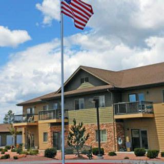 A two-story building with an American flag flying in front under a partly cloudy sky.