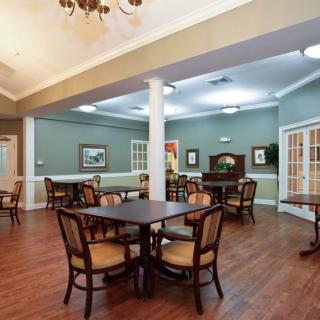 A spacious dining room with neatly arranged tables and chairs, featuring elegant lighting and decor.