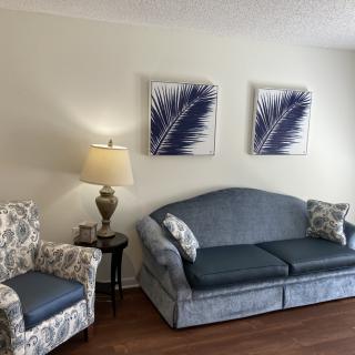 A cozy living room featuring a blue sofa, patterned armchairs, and decorative wall art.