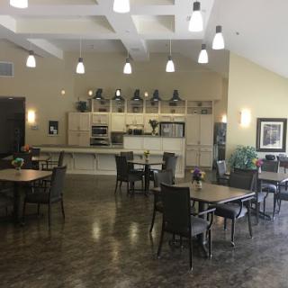 A spacious and modern dining area featuring tables, chairs, and an open kitchen.
