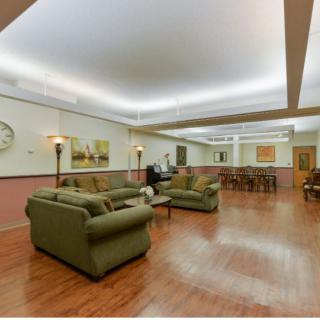 A spacious living room with green sofas, wooden flooring, and elegant lighting.