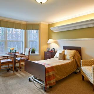 A well-lit hospital room featuring a bed, table, and chairs, designed for comfort and care.