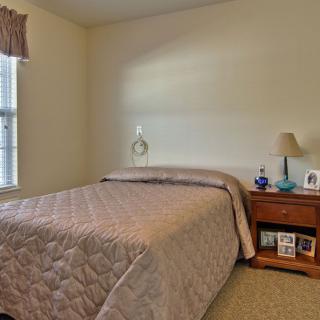 A cozy bedroom with a neatly made bed and a nightstand beside it.