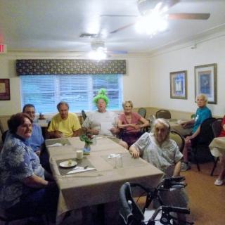 A group of elderly people gathering and socializing in a dining room.